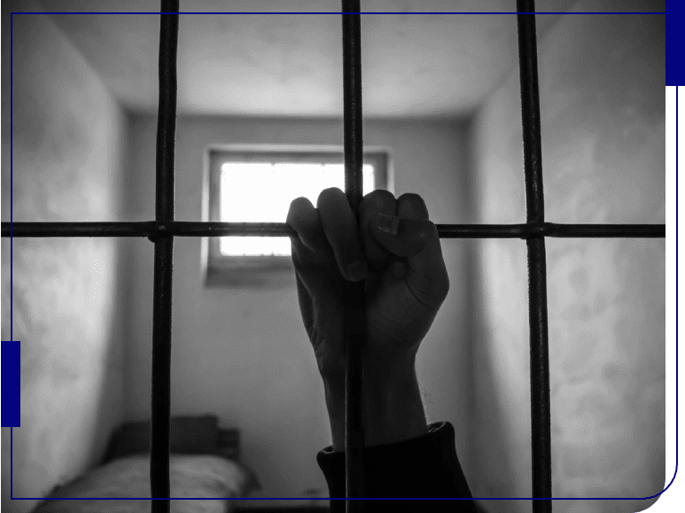 A person 's hand is seen through bars of an inmate cell.