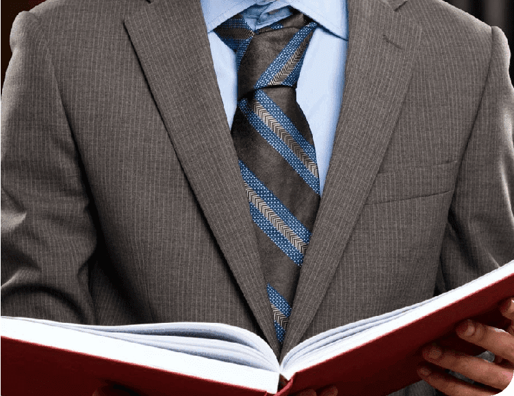 A man in suit and tie holding an open book.